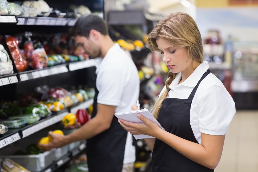 woman writing on notepad in grocery section of store