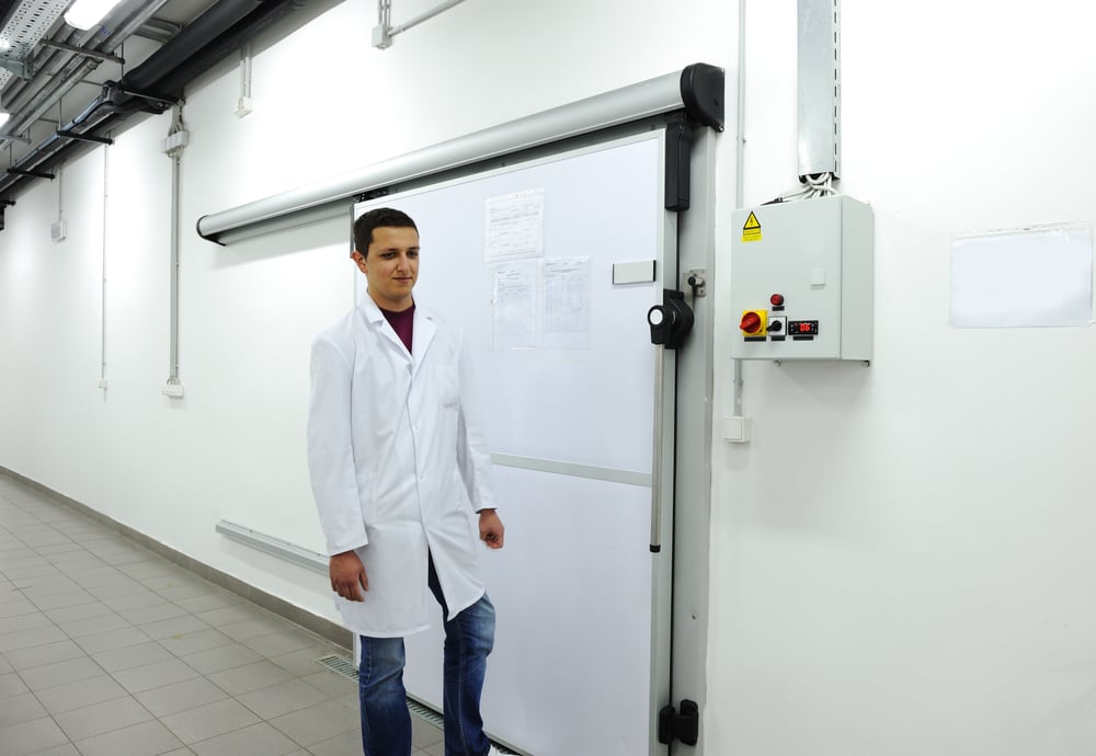 Young worker opening door of cooler